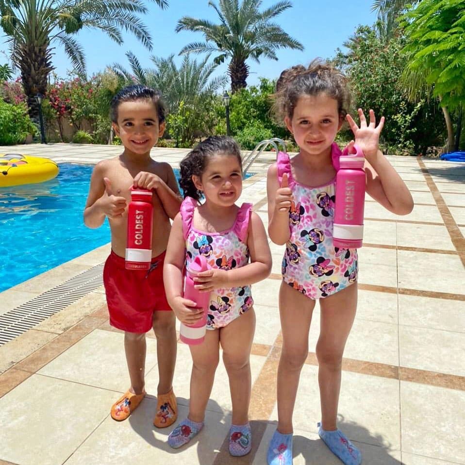 Kids playing in a pool with a Coldest bottle